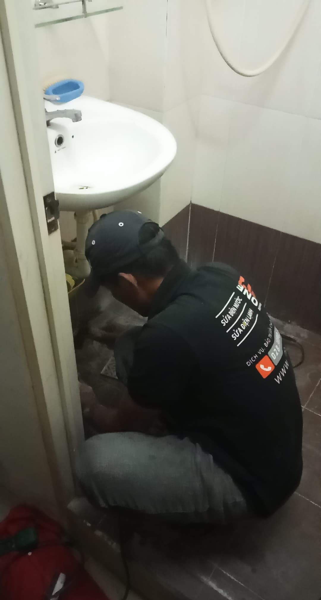 Thợ 1Fix đang kiểm tra, siết lại các điểm kết nối của bồn rửa mặt bị lỏng lẻo.