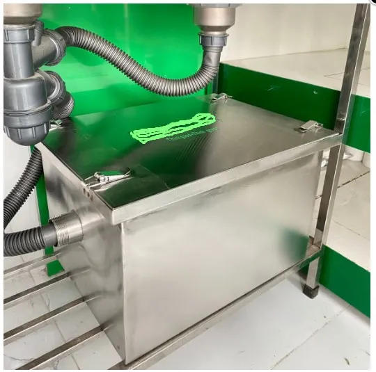 Một bể tách mỡ 3 ngăn bằng inox đã được lắp đặt hoàn chỉnh dưới gầm chậu rửa công nghiệp.