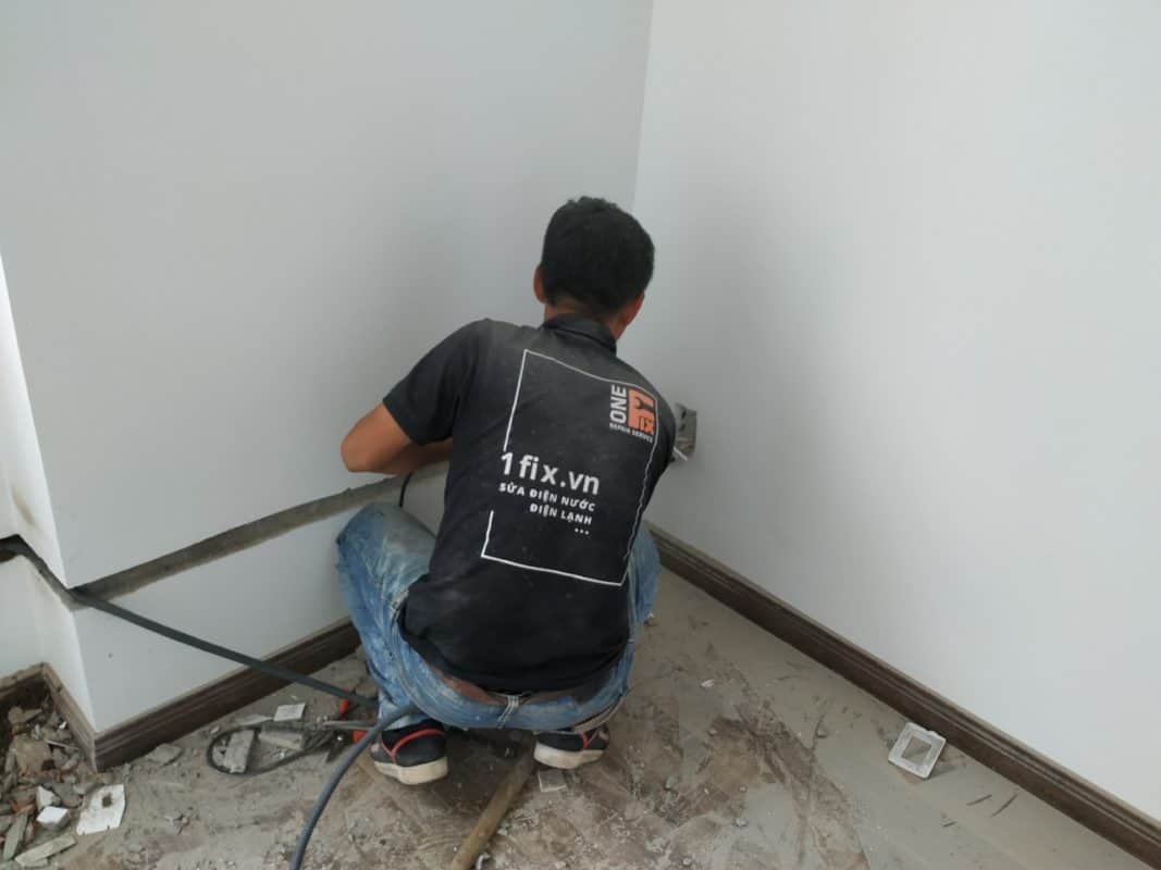 Thợ điện 1Fix đang đi dây điện âm tường cho ổ cắm mới một cách chuyên nghiệp và cẩn thận.