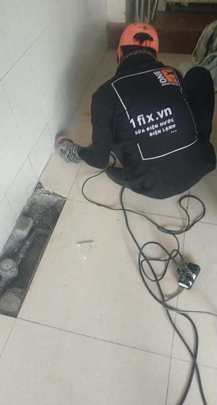 Thợ 1Fix đang xử lý điểm rò rỉ nước dưới sàn nhà vệ sinh