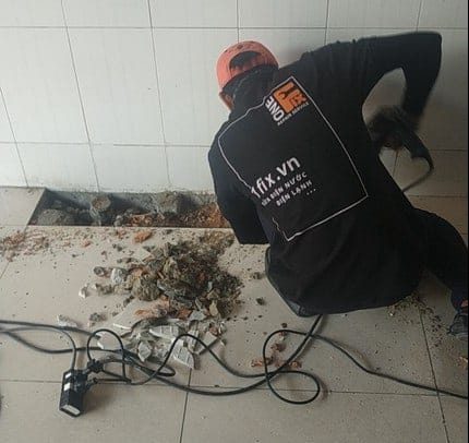 Thợ 1Fix đang sử dụng máy dò chuyên dụng để tìm chính xác vị trí rò rỉ nước âm dưới sàn nhà tại TPHCM.