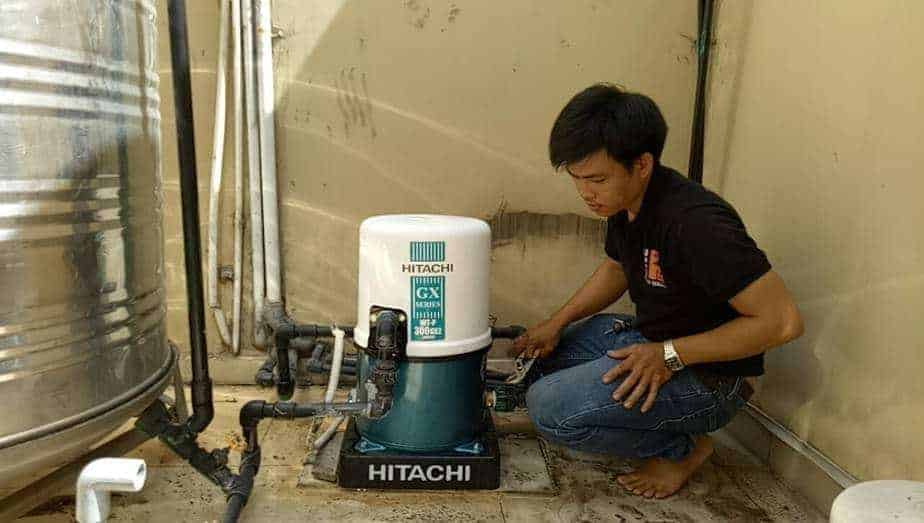 Thợ 1Fix lắp đặt máy bơm tăng áp Hitachi ngoài trời, đảm bảo an toàn điện và hiệu suất hoạt động.