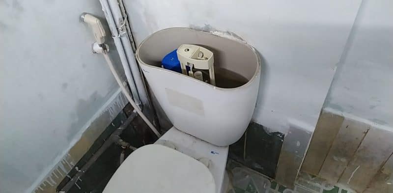 Thợ đang kiểm tra bộ ruột bồn cầu bị rò rỉ nước liên tục