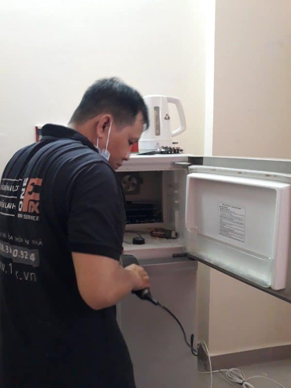 Kỹ thuật viên đang kiểm tra block và hệ thống ống dẫn gas phía sau tủ lạnh.