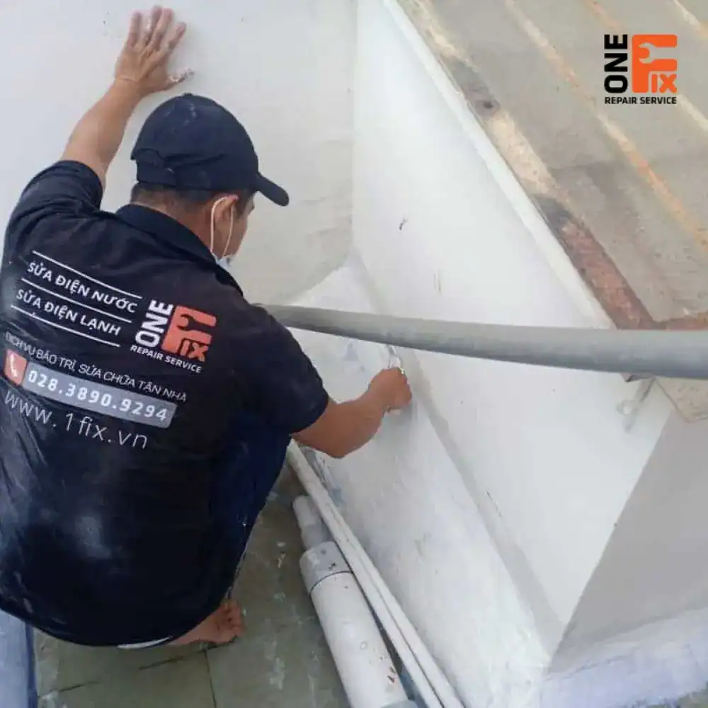 Thợ 1Fix đang cạo lớp sơn cũ bong tróc trên tường trước khi thi công chống thấm