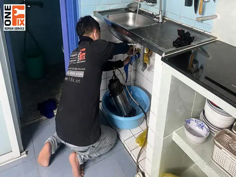 Nhân viên của 1FIX đang lau dọn sạch sẽ sau khi sửa xong vòi nước bồn rửa chén.